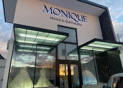 Fachada de la boutique Monique de noche con vestidos iluminados